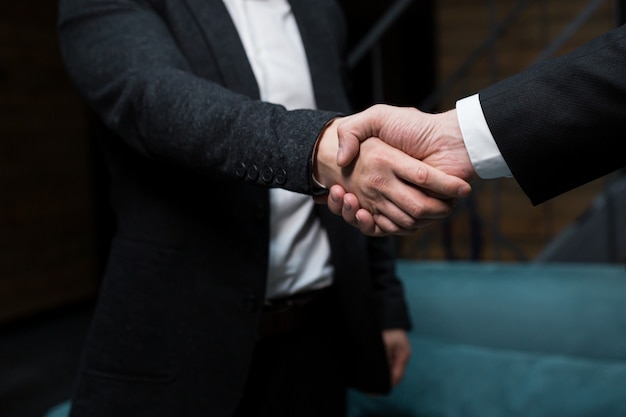 Photo close up photo two men in black business suits shaking hands