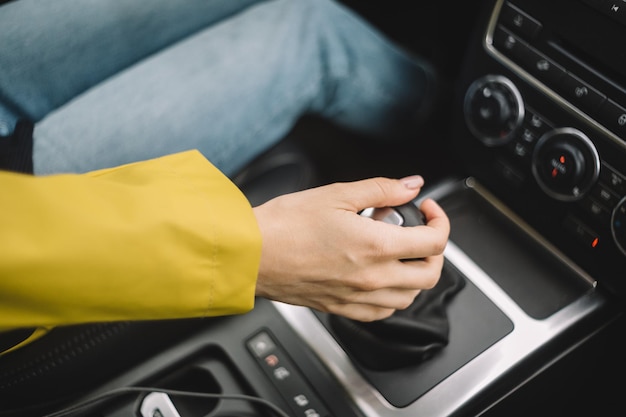 Photo close up photo of unrecognizable girl which switches gears in the car by hand female drive the car