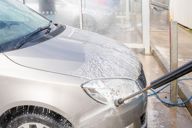 A close up photo of a washing a car with a jet wash in the open air