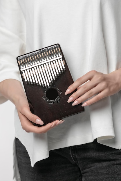 Foto ravvicinata di mani di donna che tengono kalimba su sfondo bianco