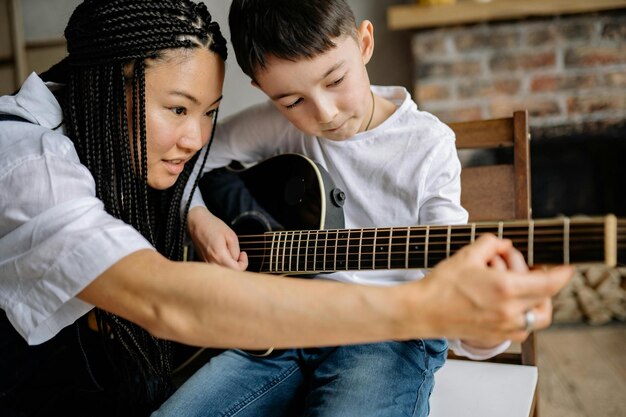 Photo close up photo of a woman teaching a boy in playing guitar stock photo