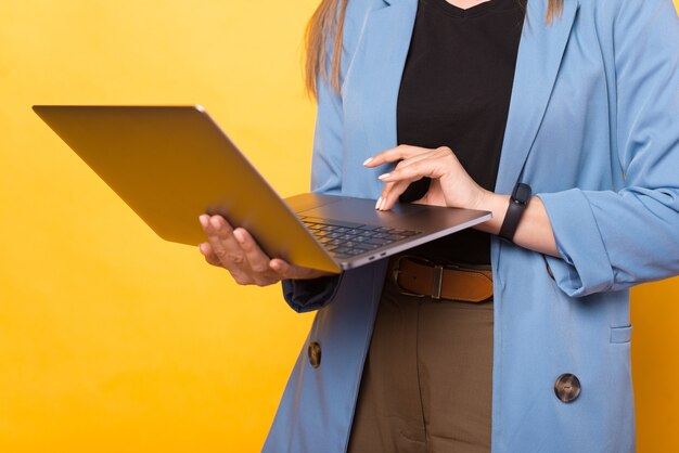 Close up photo of woman working at laptop over yellow background