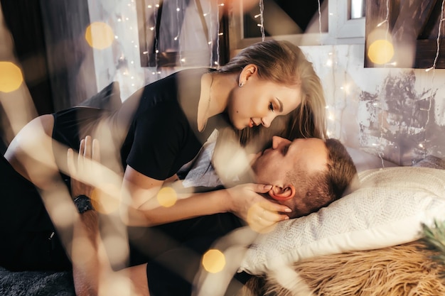 Close up photo of a young couple in an embrace on the bed during New Years Emotions passion youth hugs and kisses for Christmas Young couple romantic new year time