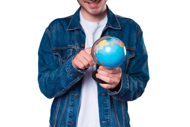 Крупным планом фото молодого человека, указывающего на земной шар