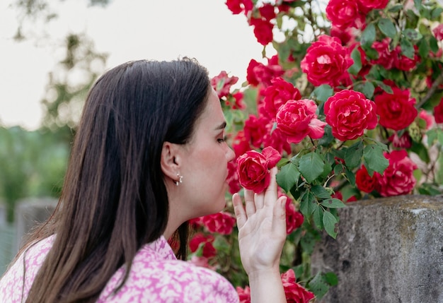 Foto foto in primo piano di una giovane donna che puzza di rose rosse in primavera