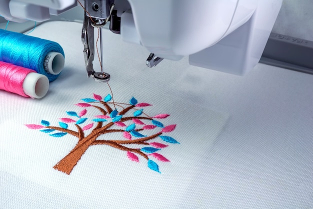 Close up picture of embroidery machine and two threads cyan and pink color.