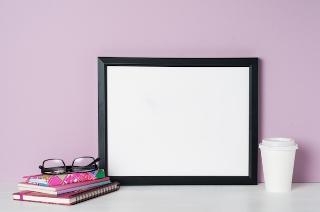 Photo close-up of picture frame with books on table against wall