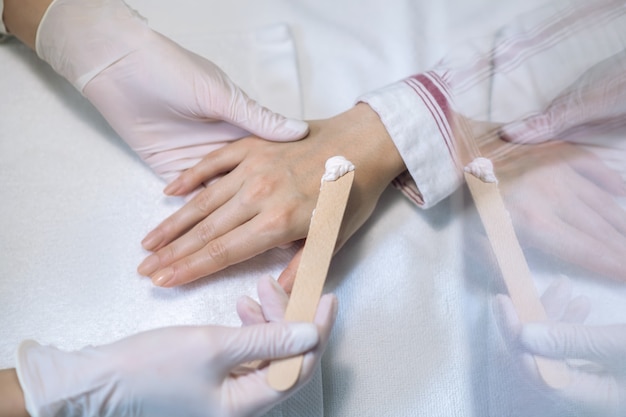 Close up picture of hands in gloves applying cream on a hand