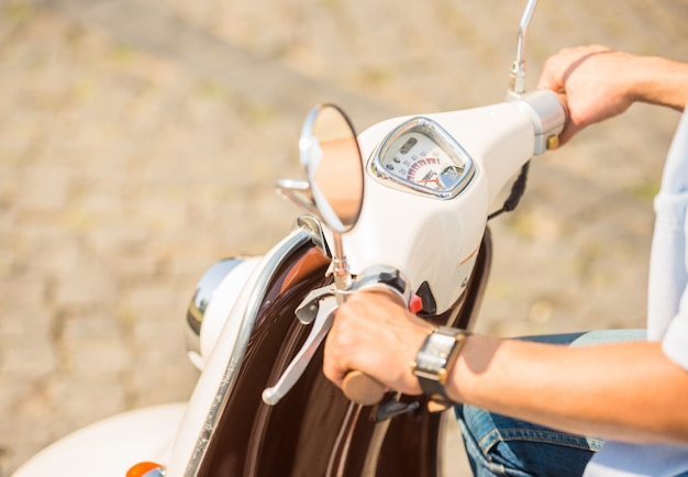 Close-up picture of a man riding on scooter outdoors.