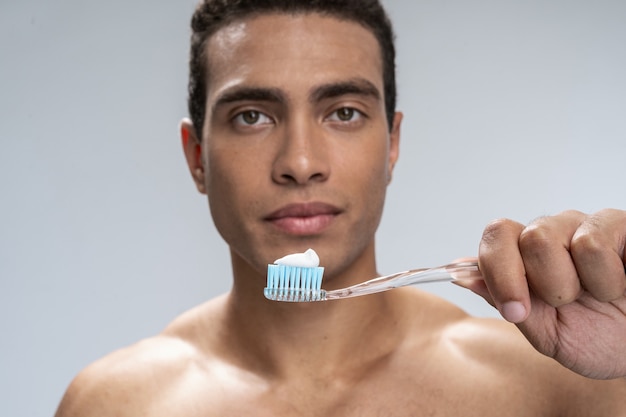 Close up picture of a toothbrush in hands of a young man