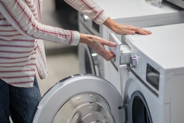 Close up picture of woman hands examining a washing machine