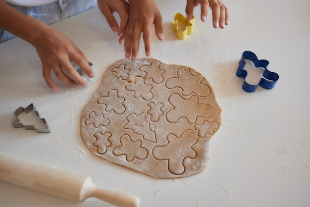 설탕 쿠키를 만들기 위해 부드러운 롤빵 반죽에 하트 모양 쿠키 커터를 누르는 어린 아이의 손 사진을 클로즈업