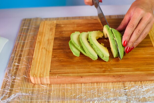 Close up picture of young lady's hands slicing crab sticks