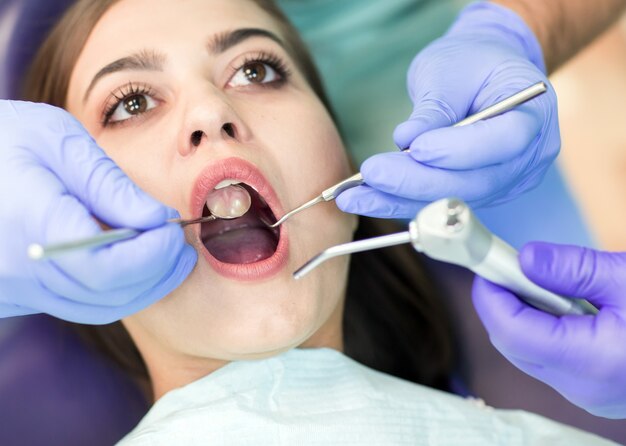 Close-up picture of young woman sitting in the dentist's chair with opened mouth at dentist's office while having examination.