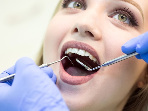 Close-up picture of young woman sitting in the dentist's chair with opened mouth at dentist's office while having examination.