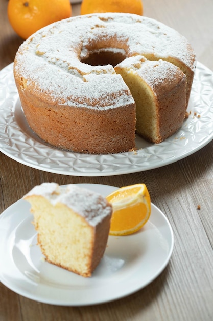 Close up piece of moist orange fruit cake on plate with orange slices on wooden table Delicious breakfast traditional English tea time Orange cake recipe