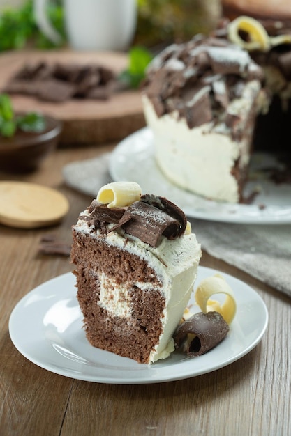 화이트 초콜릿과 다크 초콜릿 케이크 두 조각을 나무 테이블에 올려놓은 생일 및 웨딩 케이크를 닫습니다