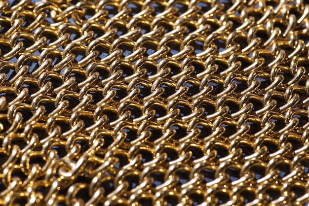 A close up of a piece of wire mesh with a gold chain.