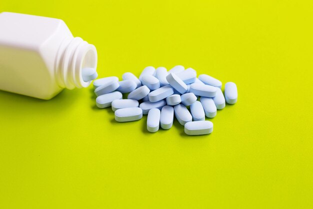 Close-up of pills and bottle on yellow background