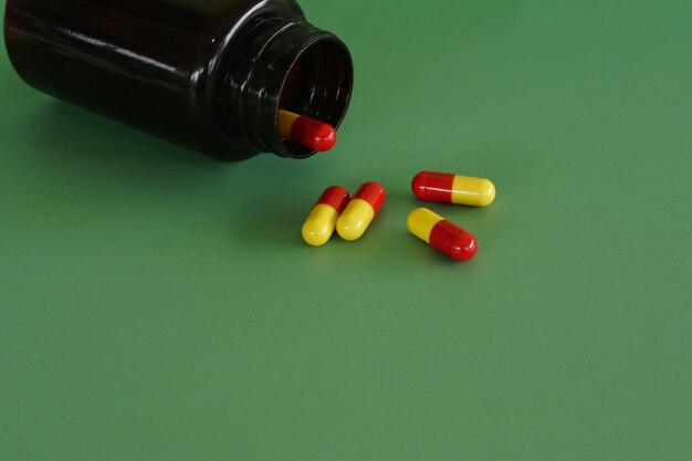 Close-up of pills spilling from bottle against white background