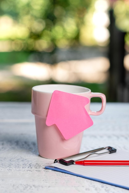 Foto close-up di un libro rosa e di una tazza di caffè sul tavolo