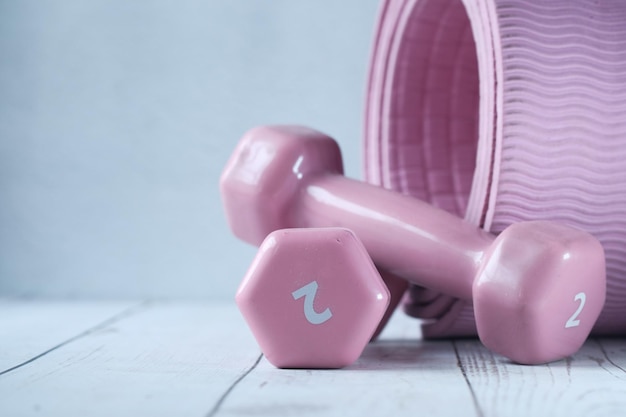 Close up of pink color dumbbell and exercise mat on table