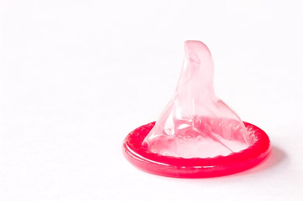 Close-up of pink condom against white background