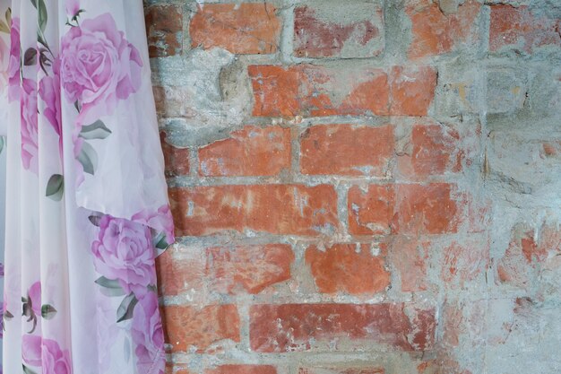 Close-up of pink curtain hanging on brick wall