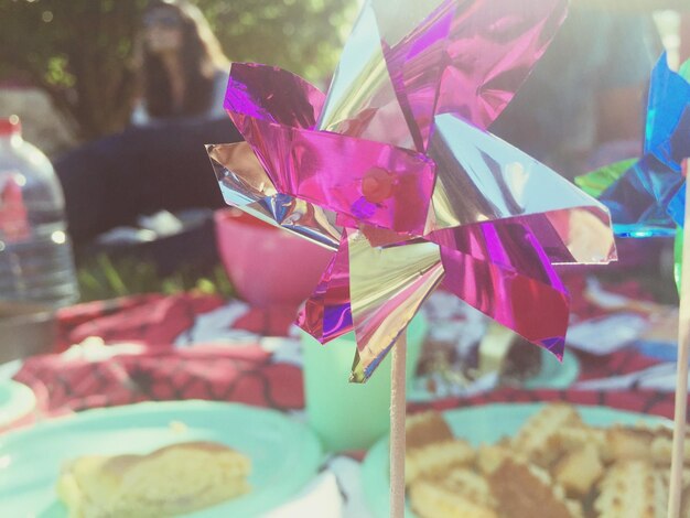 Photo close-up of pink pinwheel against food on table