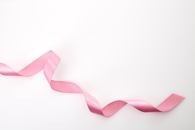 Photo close-up of pink ribbon over white background