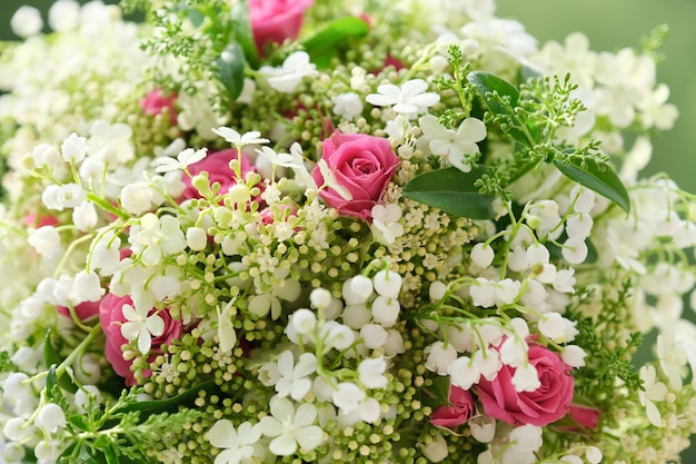 Close-up of pink roses flowers and white lily of the valley with drops