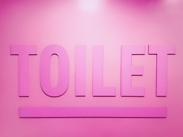 Close-up pink toilet text on pink wall