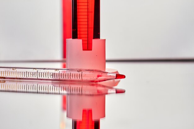 Foto close up pipetta con campione di sangue sulla superficie riflettente analisi del sangue e analisi nella ricerca medica