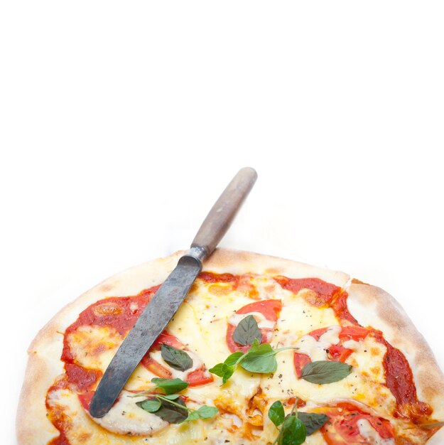 Клоуз-ап пиццы с ножом на белом фоне