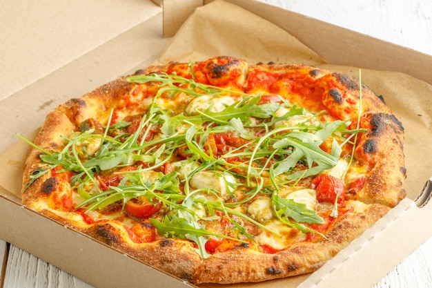 Close up of pizzas with variety of greens and cheese in cardboard