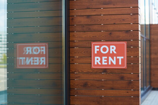 Close-up of placard For Rent hanging on the wall of new office building