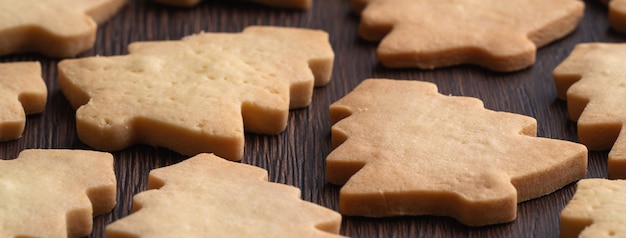 Close up of plain flavor gingerbread Christmas tree cookie on wooden table background. Food for Christmas holiday celebration.