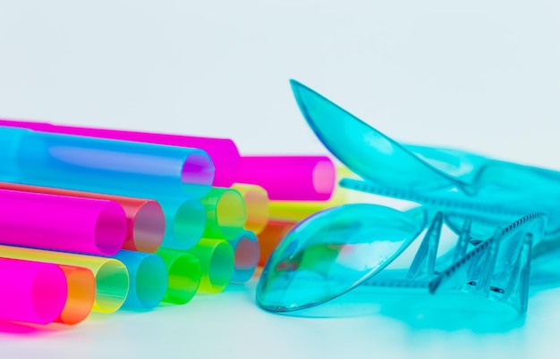 Close-up of plastic eating utensils and drinking straws over gray background