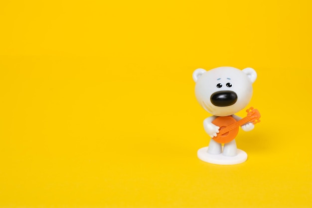 Close up of a plastic toy white grey bear with guitar on yellow background