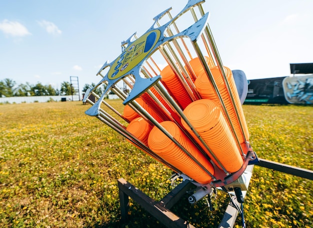 Close up plat machine with orange shooting plate for shootingground training on field with grass