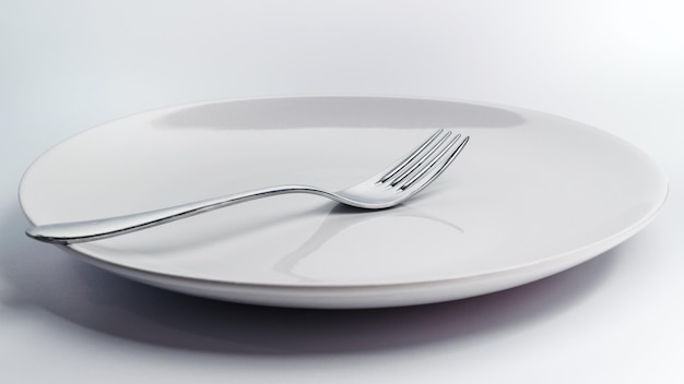 Close-up of plate with fork on white background