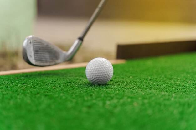 Close-up playing in mini-golf on the green grass using niblick