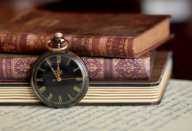 Foto prossimo piano di un orologio da tasca e un libro sul tavolo