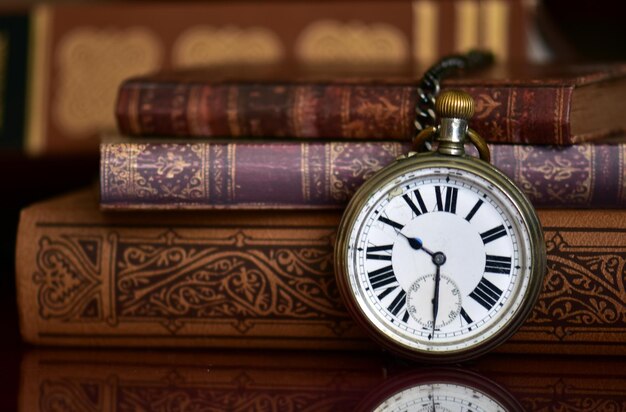 Close-up of pocket watch and books on table