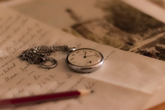 Photo close-up of pocket watch and pencil on paper