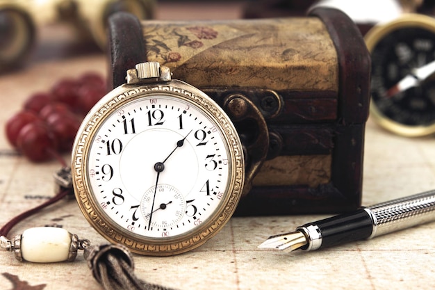 Foto close-up di un orologio da tasca con scatola e penna sul tavolo