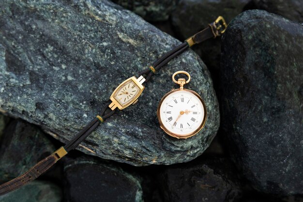 Photo close-up of pocket watch and wristwatch on rock