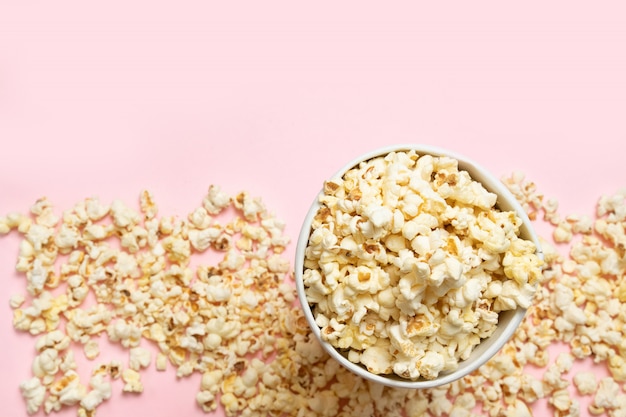 Close-up popcorn on pink background. Unhealthy diet concept. Minimalism, flat lay, top view, place for text.