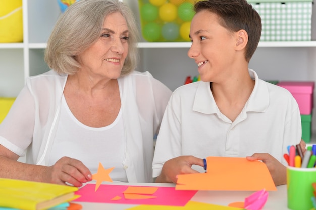 Close up porait of grandmother teaches her grandson to do craft items