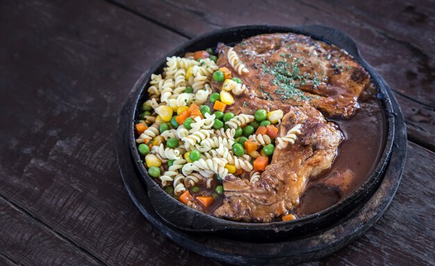 Photo close up pork steak on hot pan serve